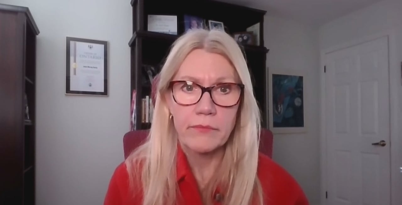 Woman with glasses and red shirt looks at camera