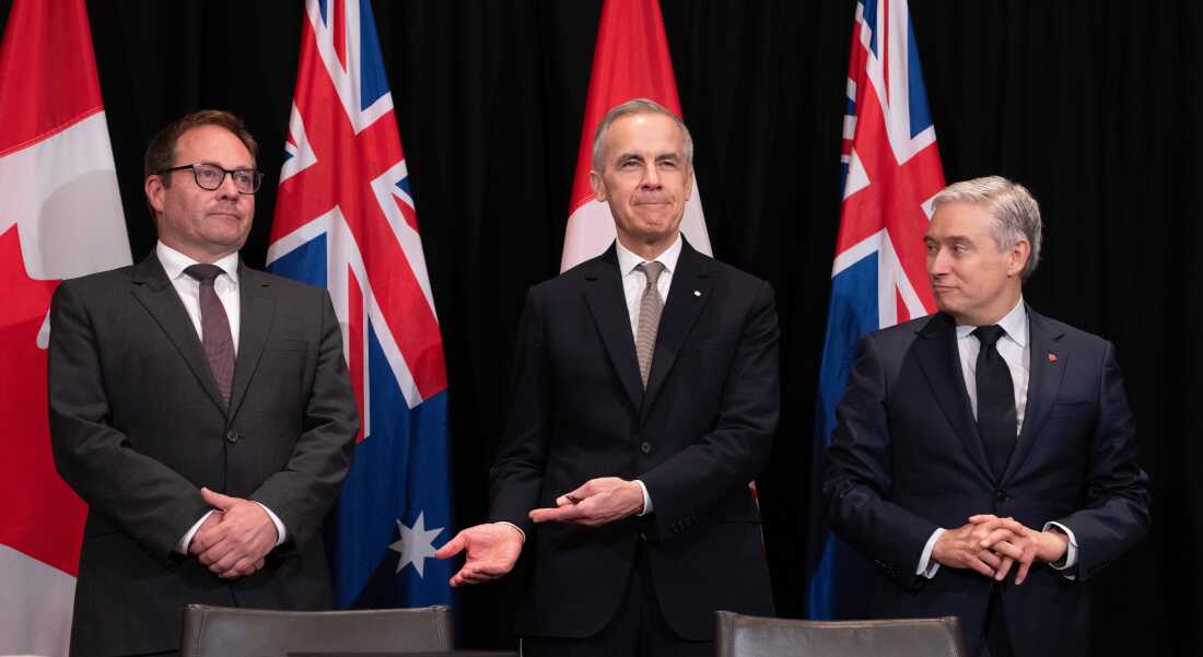 Canada's Prime Minister Mark Carney, center, gestures to Daniel Mulino, Australian Assistant Treasurer as he is introduced at the start of a signing ceremony, as Canada's Finance and National Revenue Minister Francois-Philippe Champagne, right, looks on, in Sydney, Australia, Wednesday, March 4, 2026. (Adrian Wyld/The Canadian Press via AP)