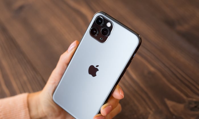 A left hand holding an iPhone with the back showing.