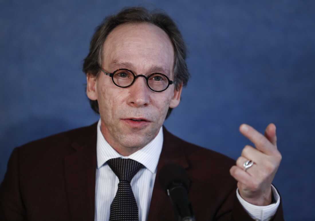 Lawrence Krauss, photographed from about the torso up, speaks during a news conference in 2017. He's wearing a suit and glasses, and he's gesturing with one hand.