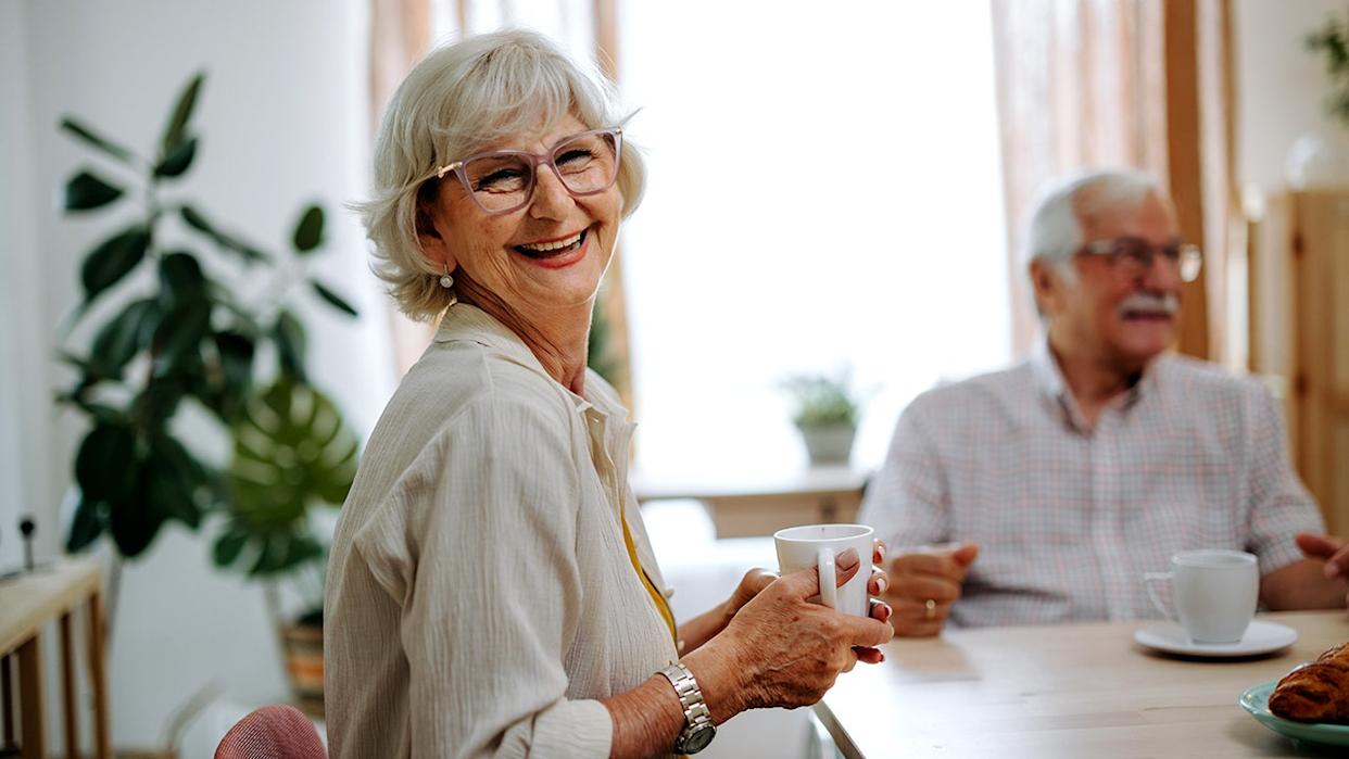 Senior woman posing for camera while sitting at the table at home