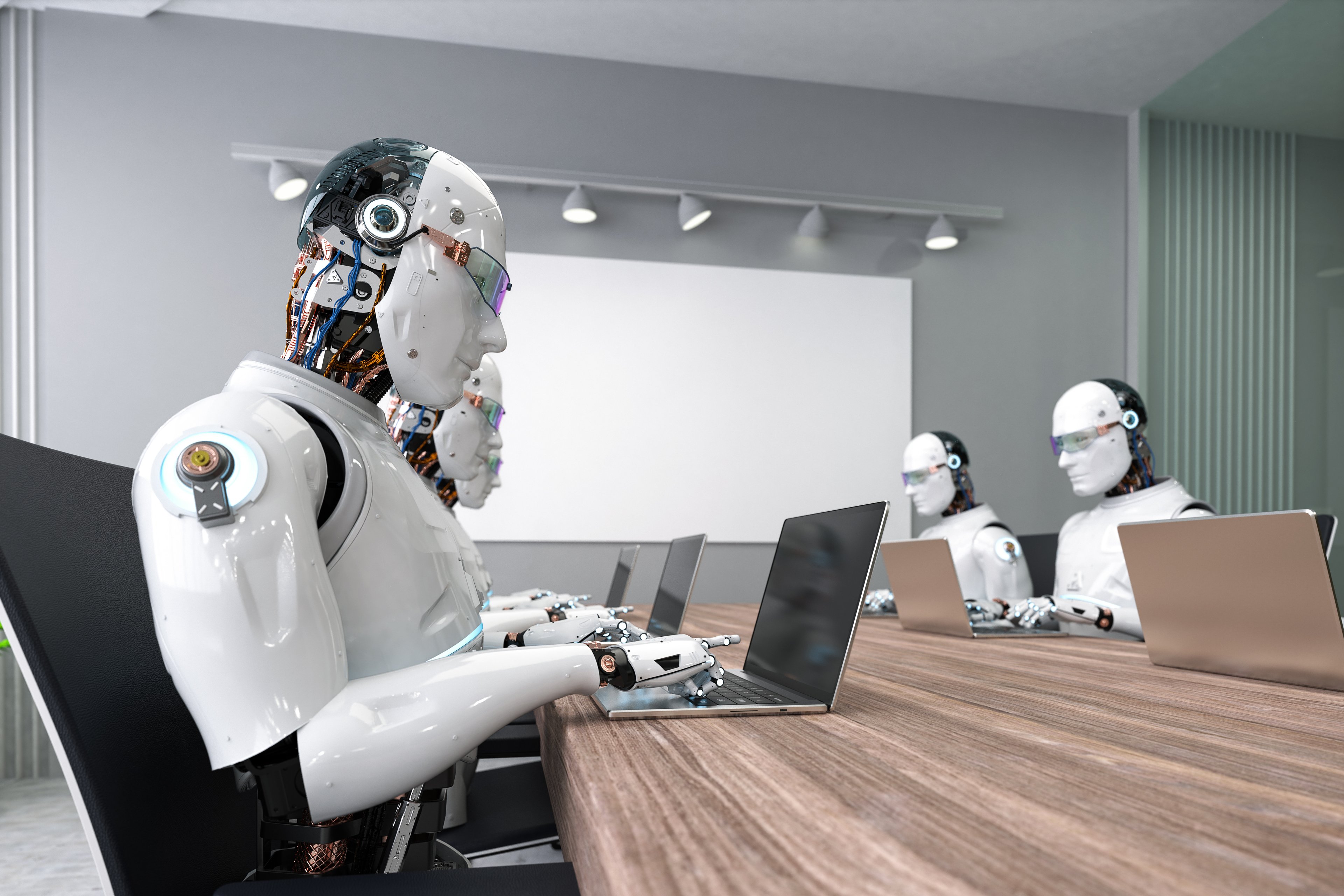 Six AI humanoid robots sitting in an office and working on laptops.