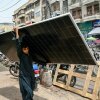 A labourer walks through Karachi with a solar panel
