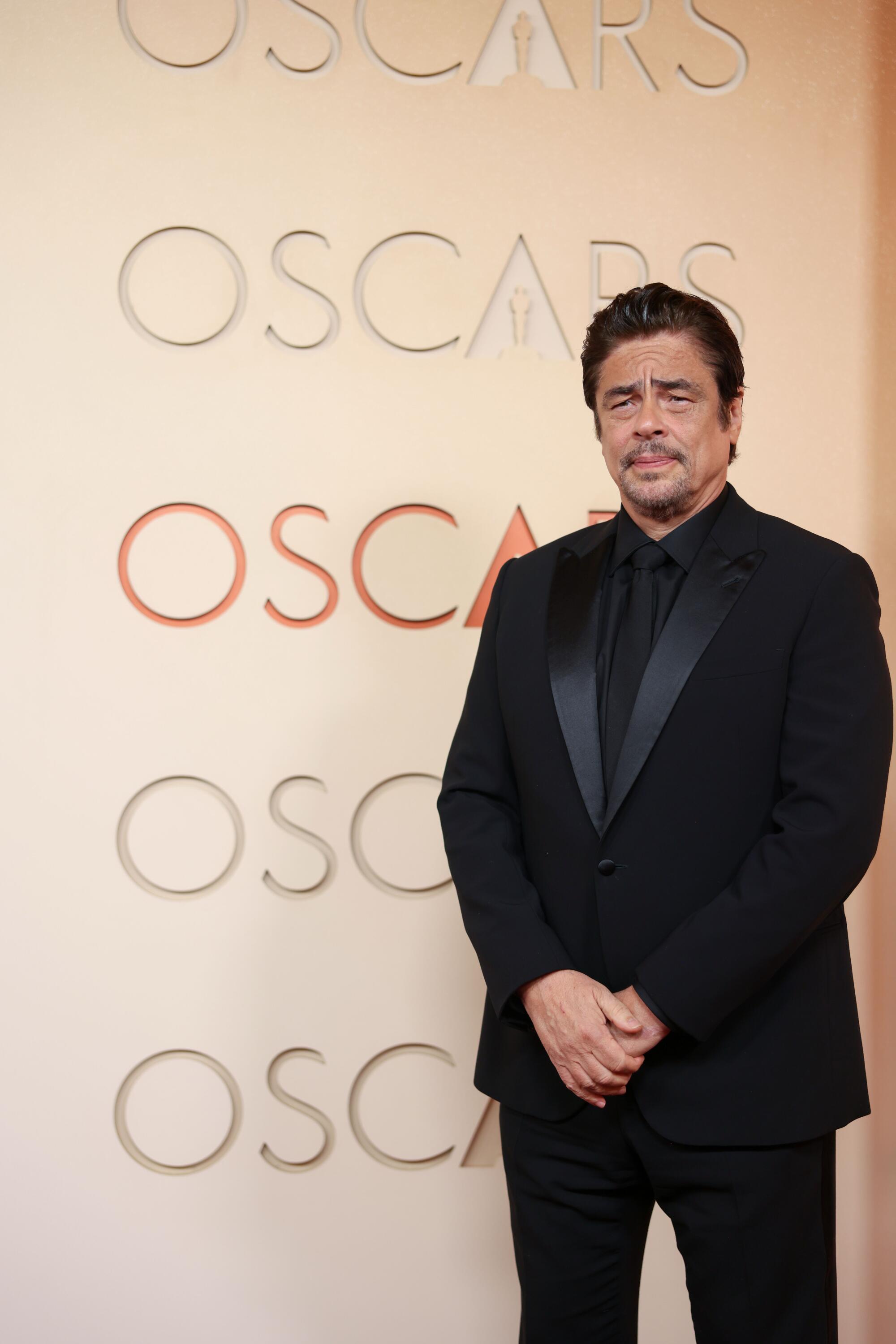 Benicio del Toro, in an all-black tux, poses on the red carpet. 