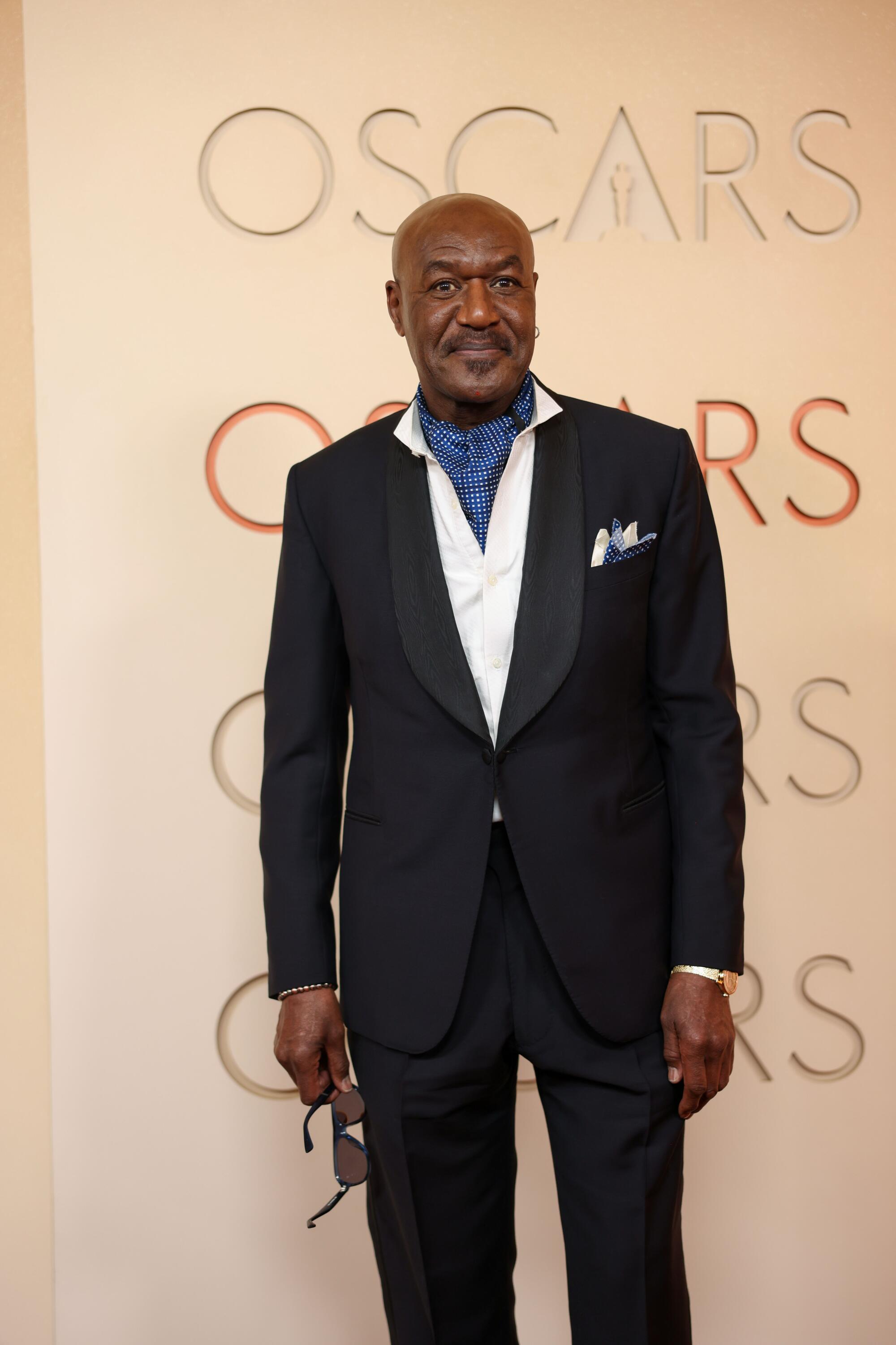 Delroy Lindo, wearing a tux with a blue necktie, poses on the red carpet. 