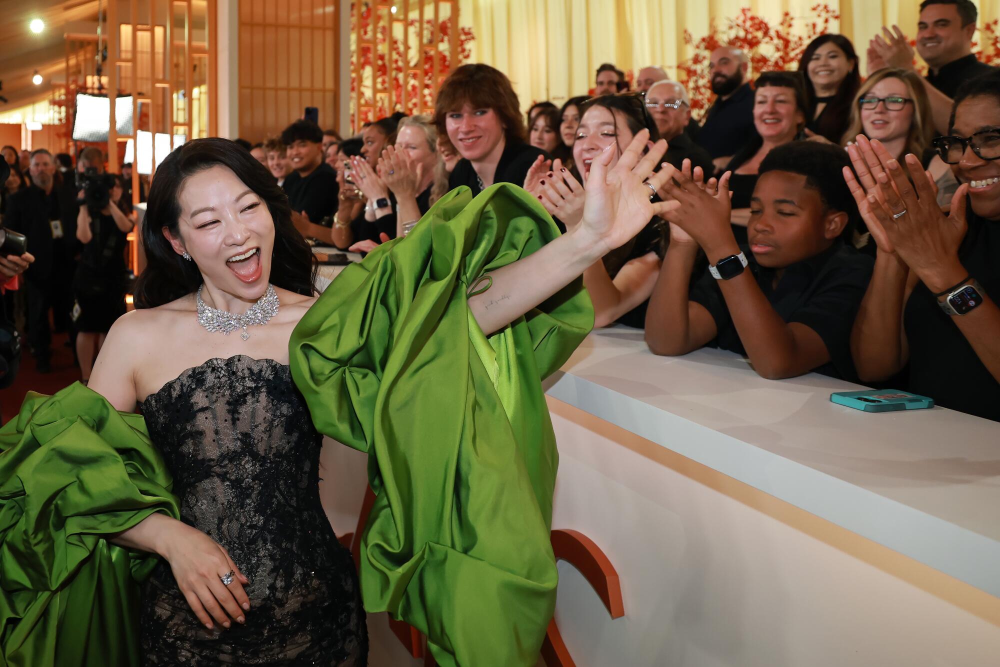 Arden Cho greets fans on the rafters of the Oscars red carpet. 