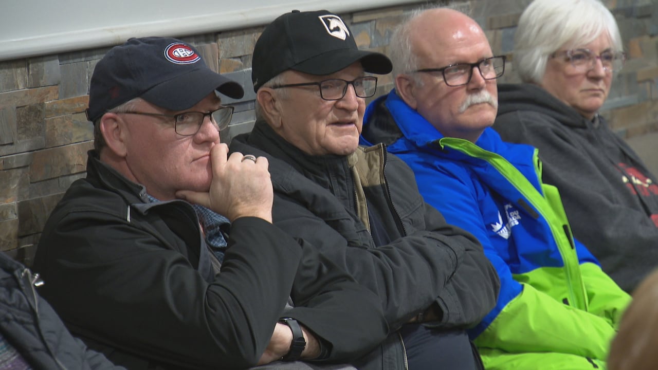 Four people sit at the back of the room listening to a speaker.