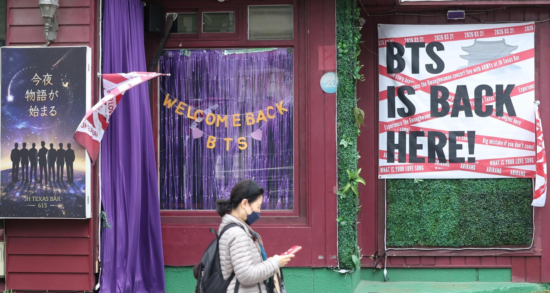 A pedestrian walks past JH Texas Bar displaying welcome messages for BTS in Jung District, central Seoul, Sunday, ahead of the boy band’s full-group comeback concert at Gwanghwamun Square this Saturday after three years and nine months. Yonhap
