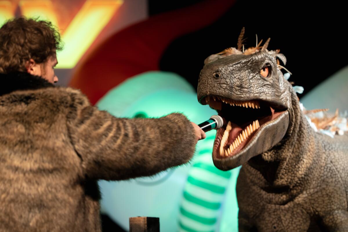 Host Shane Hartline holds a conversation with a life-size dinosaur puppet.