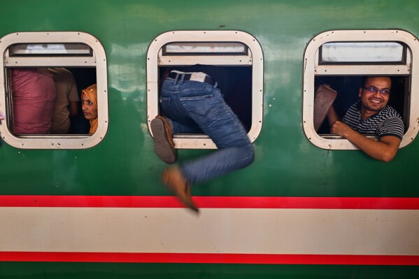 Homebound travelers scramble to board a train at Kamalapur Railway Station, joining the massive annual exodus to celebrate Eid al-Fitr, in Dhaka, Bangladesh, Wednesday, March 18, 2026. (AP Photo/Mahmud Hossain Opu)