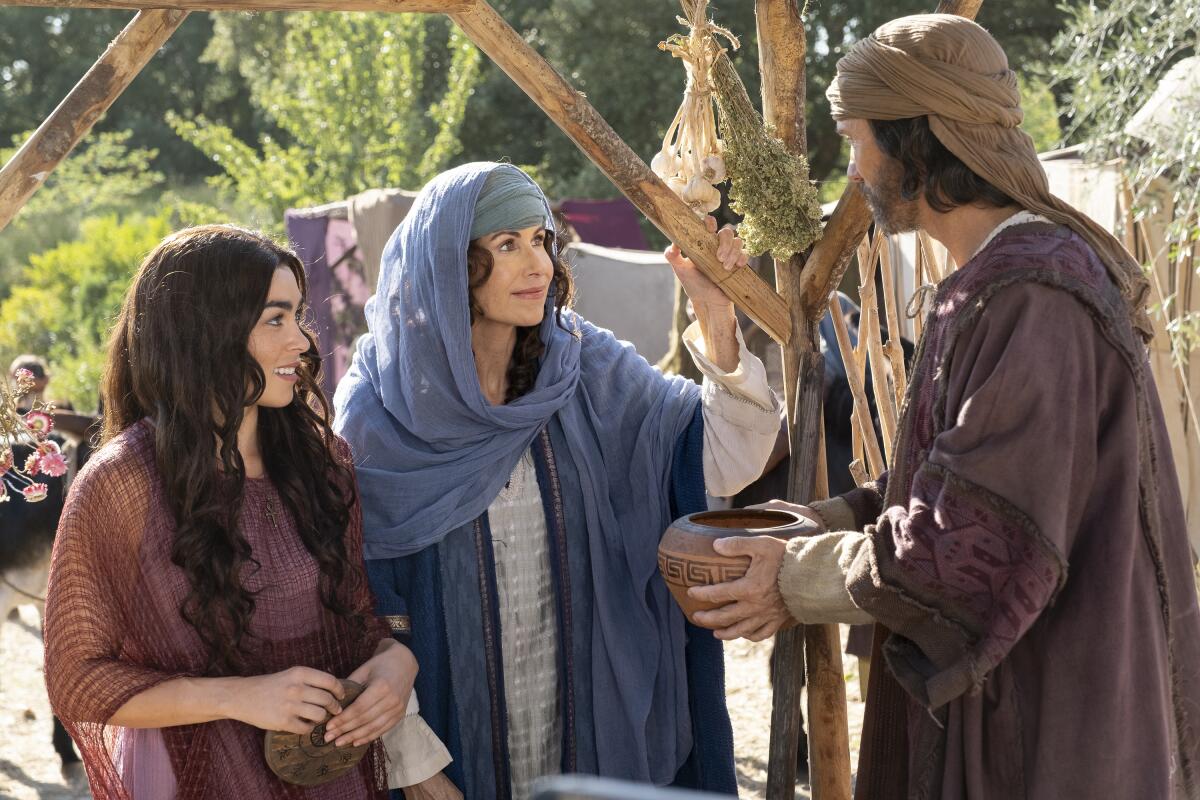 Two women look at a man holding a clay pot in both hands.