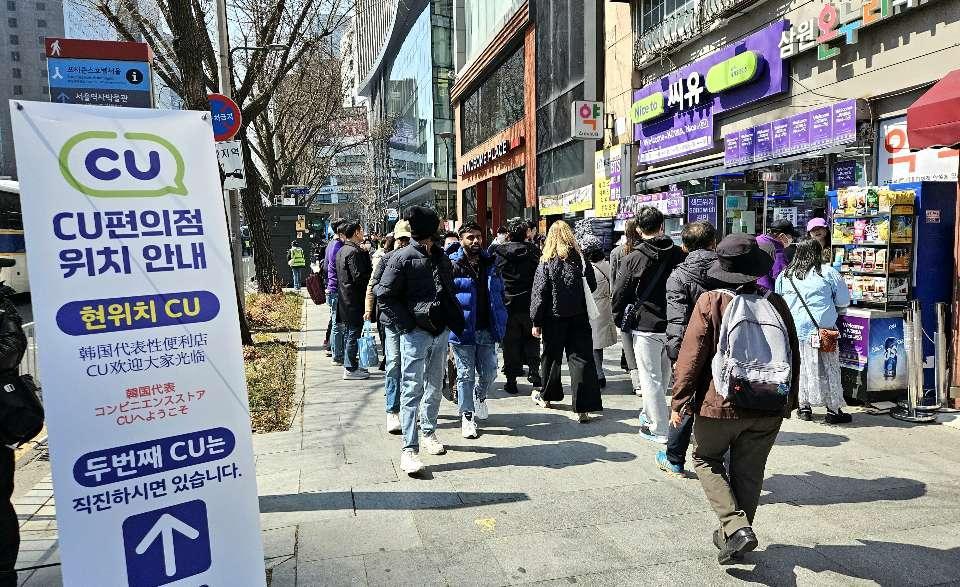 A convenience store near Gwanghwamun Square in Seoul is crowded with customers, Saturday. A banner on the left reads