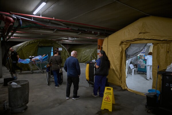 Medical staff transfer patients in a temporary emergency ward set up in a parking garage used as a shelter beneath Sheba Medical Center in Ramat Gan, Israel, Tuesday, March 17, 2026. (AP Photo/Oded Balilty)