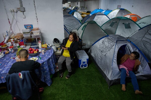People sit around a makeshift dinner table with groceries beside tents as they take shelter beneath Tel Aviv's central bus station as a precaution against possible Iranian missile attacks, Thursday, March 12, 2026. (AP Photo/Oded Balilty)