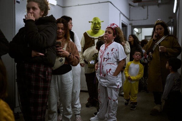 People, some wearing costumes for the Jewish holiday of Purim, gather in an underground metro station used as a shelter against possible Iranian missile attacks in Ramat Gan, Israel, Monday, March 2, 2026. (AP Photo/Oded Balilty)