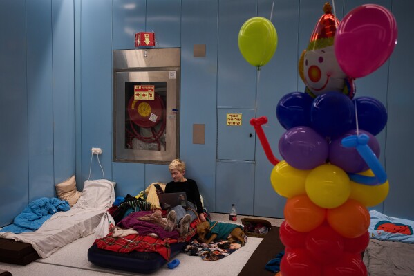 A woman sits on a mattress in an underground metro station serving as a bomb shelter amid the threat of possible Iranian missile attacks during the Jewish holiday of Purim in Ramat Gan, Israel, Monday, March 2, 2026. (AP Photo/Oded Balilty)