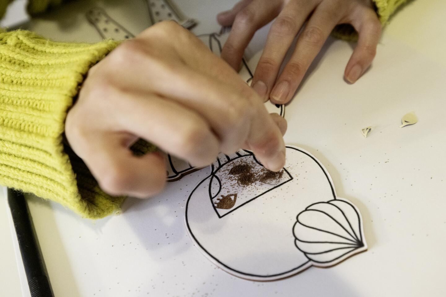 Japanese artist and illustrator Naoshi drizzles sand on a sunae project