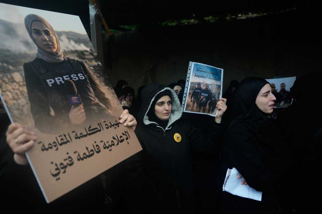 Women hold posters showing Al-Mayadeen TV reporter Fatima Ftouni, left, and, in another poster, Hezbollah's Al-Manar TV correspondent Ali Shoeib, center, and cameraman Ali Ftouni during their funeral at a temporary cemetery in Dahiyeh, Beirut's southern suburbs, Beirut, Lebanon, Sunday, March 29, 2026.