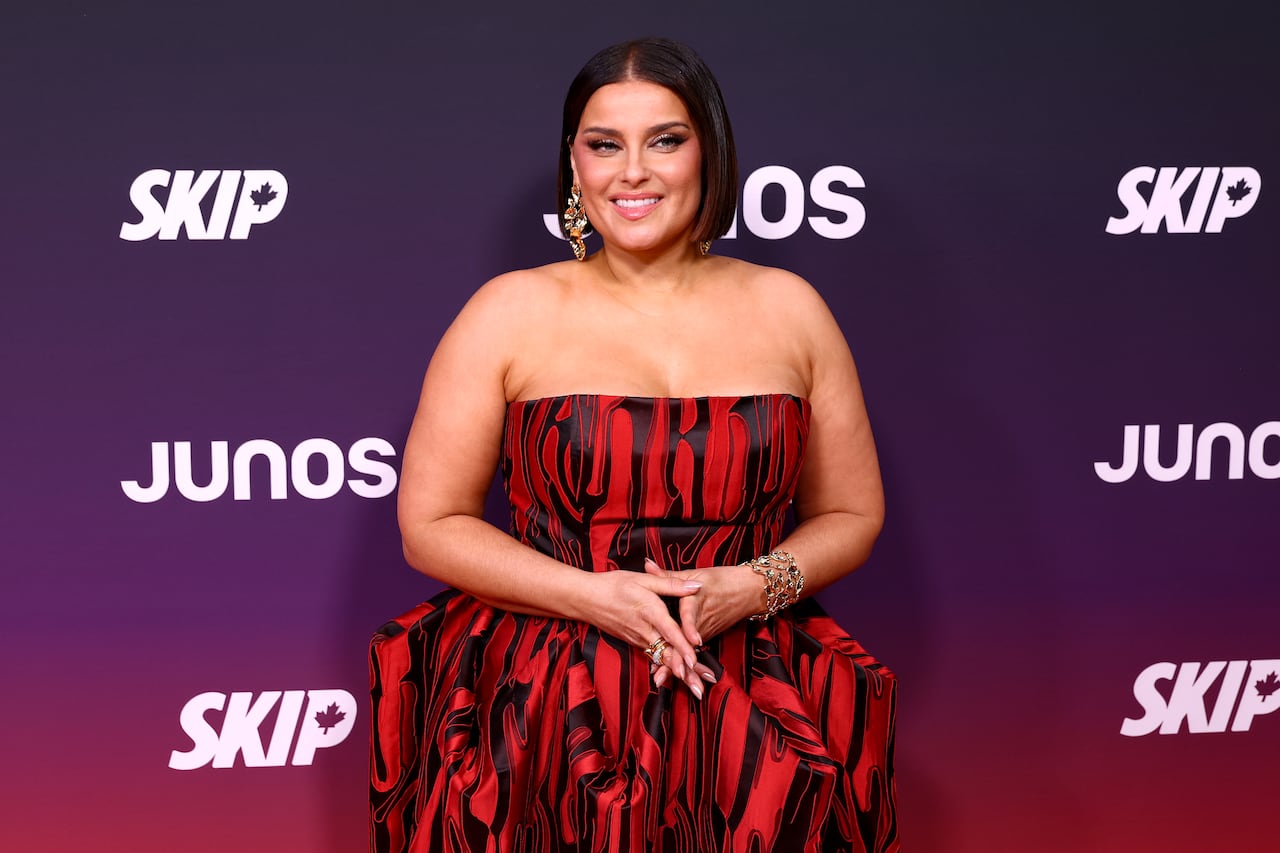A woman in a red dress poses in front of a photowall