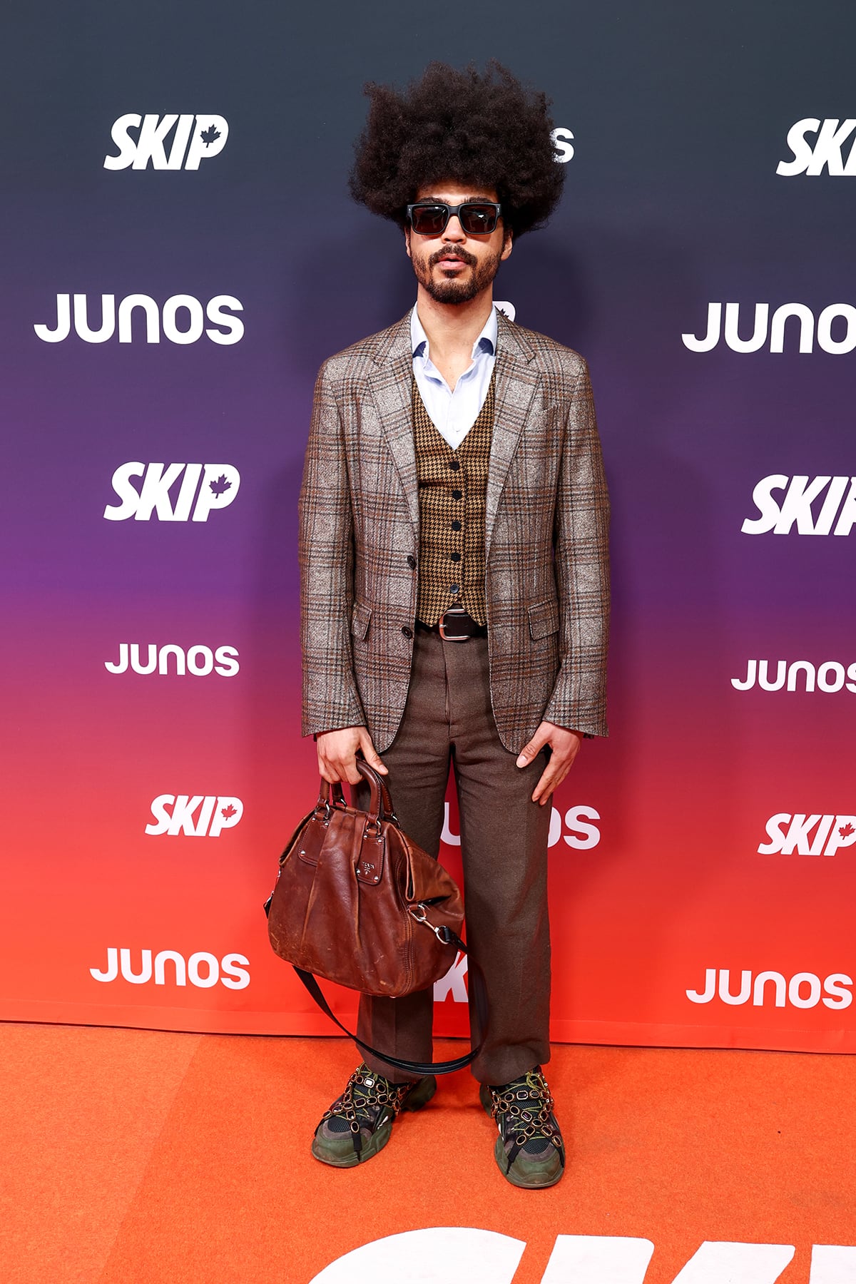A man poses for photos wearing a mixed-pattern, tailored suit.