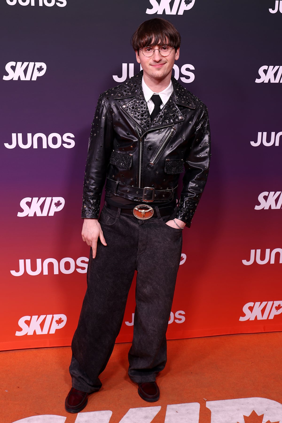 A man poses on an orange carpet.
