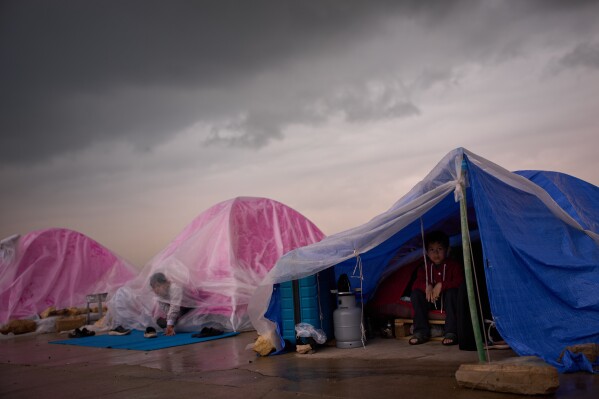 Children displaced from Beirut's southern suburb of Dahiyeh shelter from the rain inside their tents along the coast in Beirut, Lebanon, Thursday, March 26, 2026. (AP Photo/Emilio Morenatti)