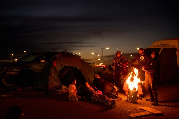 Members of a family, who fled Israeli strikes in southern Lebanon, sit around a bonfire outside a tent used as a shelter in Beirut, Lebanon, Wednesday, March 25, 2026. (AP Photo/Emilio Morenatti)