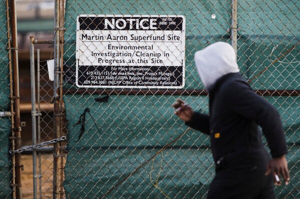 A man walks past a notice for the Martin Aaron Inc. Superfund site in Camden, N.J., Dec. 11, 2017. (AP Photo/Matt Rourke, File)