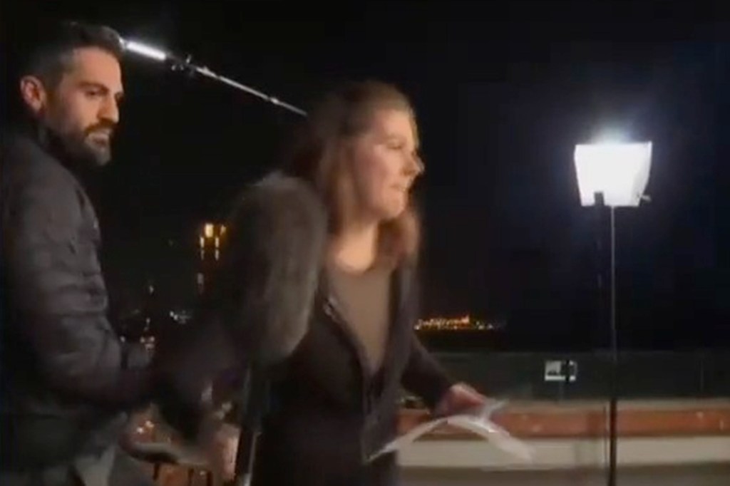 A CNN crew member and a reporter take cover during a remote interview in Tel Aviv as explosions are heard.