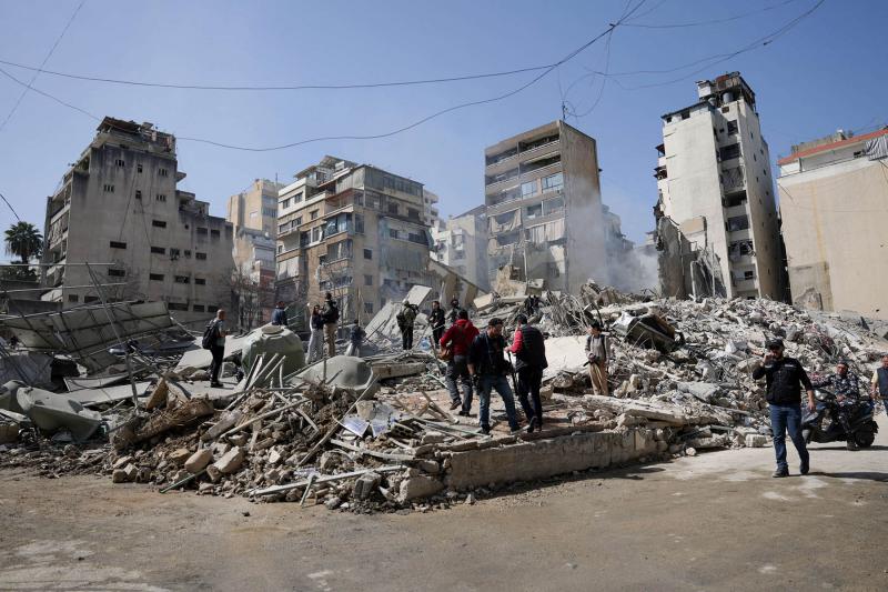 People walk amidst debris at the site of an Israeli strike in Zuqaq al-Blat district in central Beirut, Lebanon.