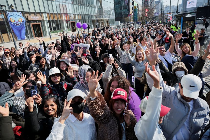 Fans of BTS cheer ahead of the band's comeback as they wait near the concert venue in central Seoul on March 21, 2026.