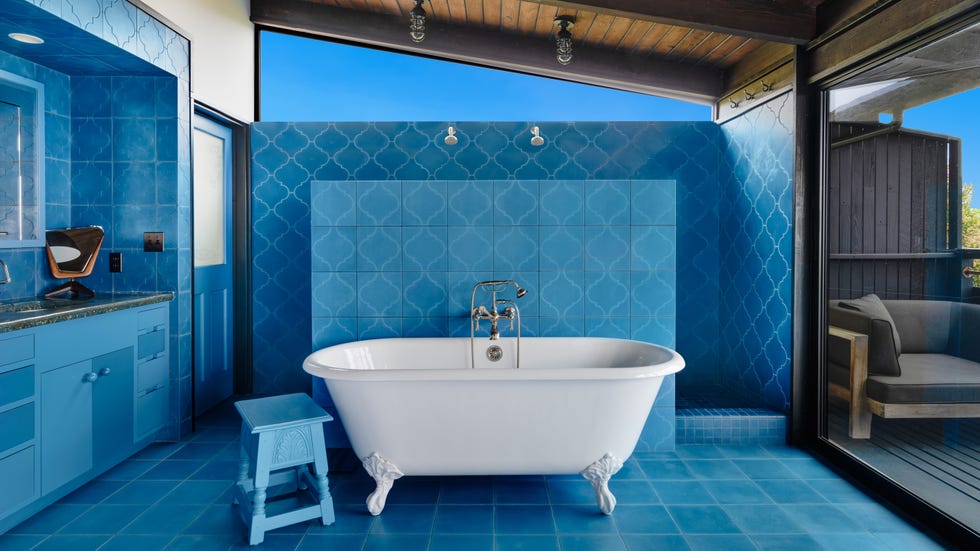 Bright blue bathroom featuring a vintage bathtub and modern elements.