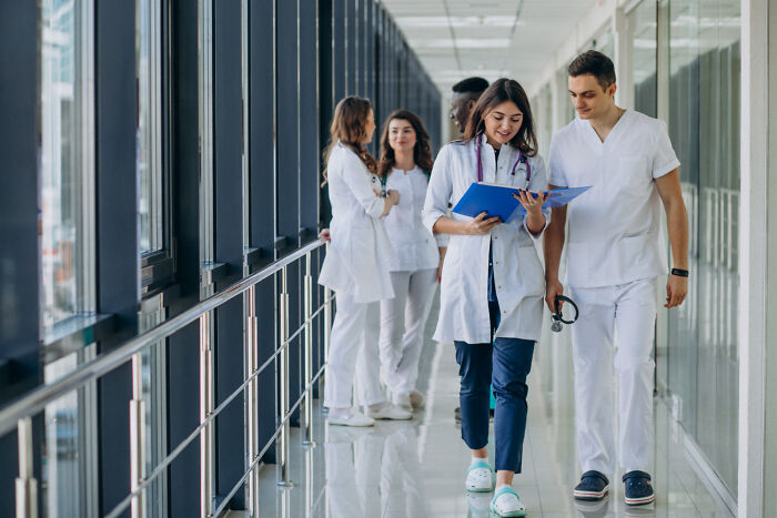 Group of medical professionals walking and talking in a hospital hallway, highlighting cases of patients faking symptoms online