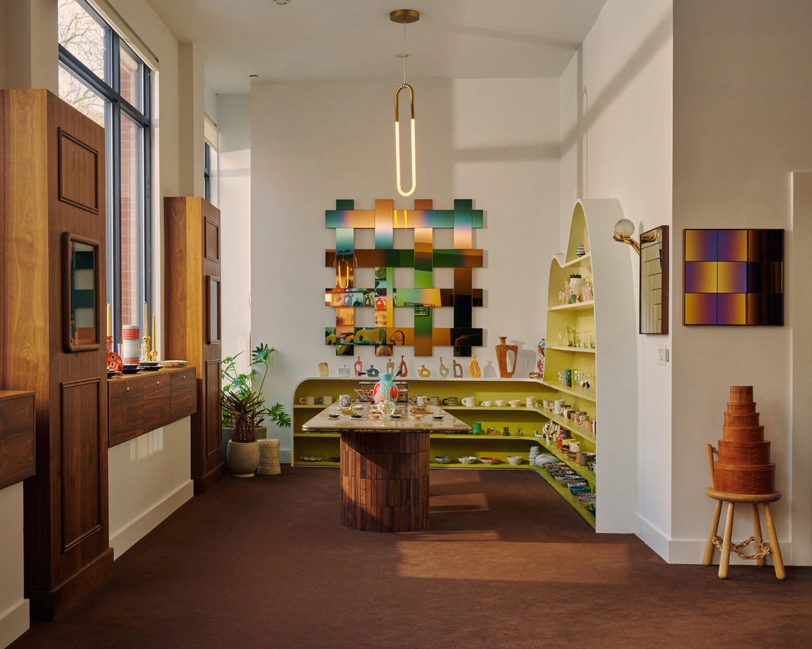 Modern interior with colorful wall art, minimalist furniture, and decorative shelves displaying various objects in a well-lit room.
