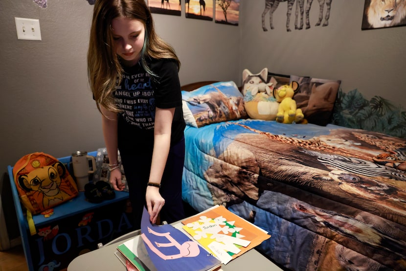 Emma Autry, 14, flips through her brother’s scrapbook of artwork in his Lion King-themed...