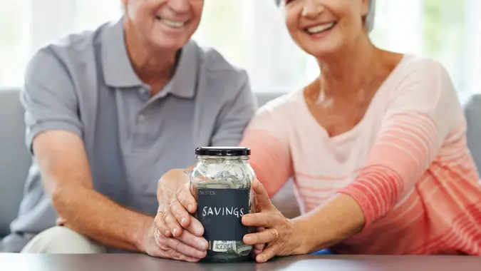 senior couple proudly posing with their savings jar