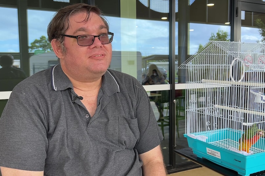 Man in glasses, with bird in cage