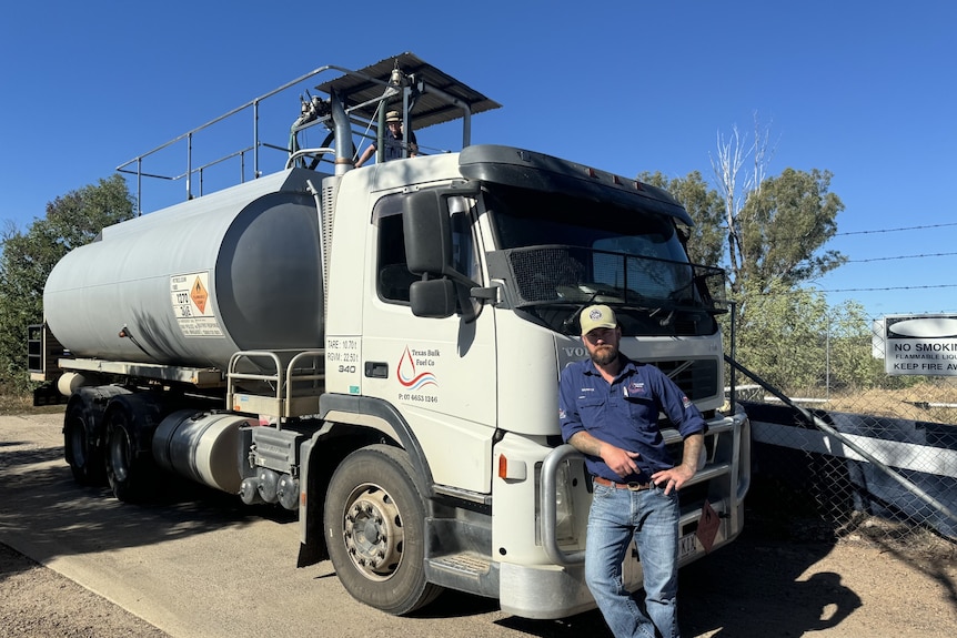 A man standing in front of a fuel tanker truck