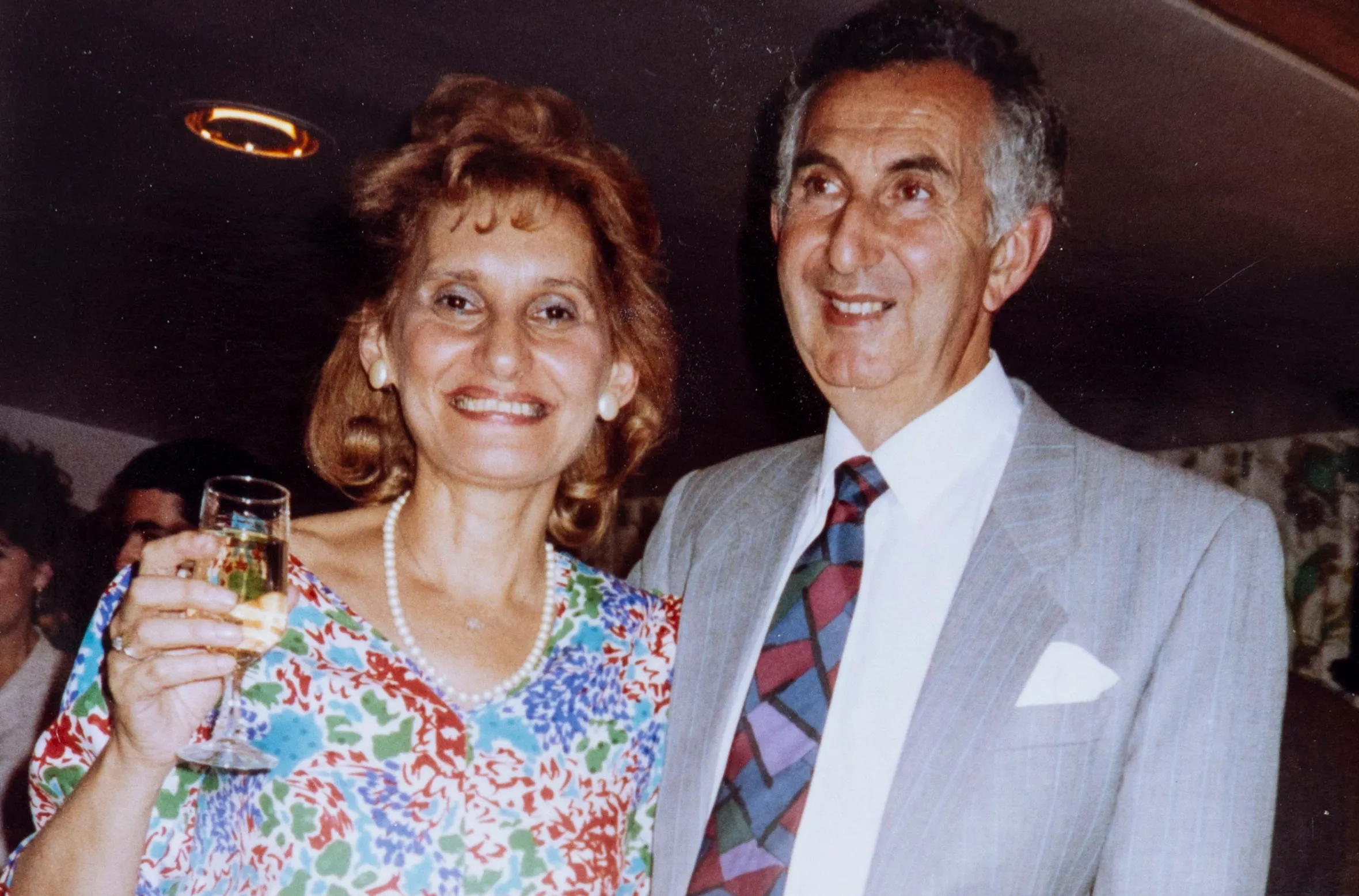 Collage of photos, with one central image of a smiling woman in a floral dress holding a glass next to a smiling man in a suit and tie.