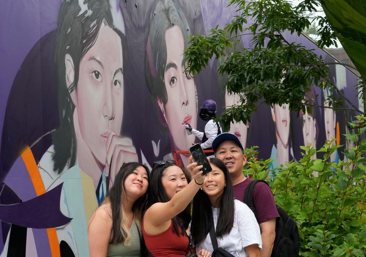 Foreign tourists take a selfie in front of a mural of K-pop band BTS members on the outer wall of a building in Seoul, in this June 14, 2023, file photo. AP-Yonhap