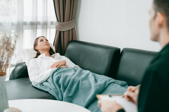Patient lying on a couch covered with a blanket during a therapy session, illustrating cases of patients faking it.