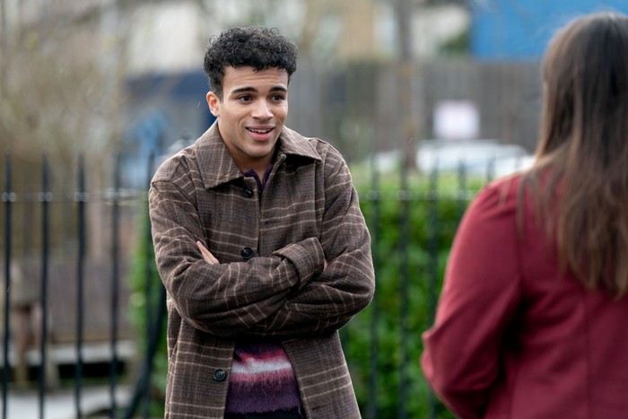 Josh stands chatting to Zoe - with his arms folded - in a scene from EastEnders