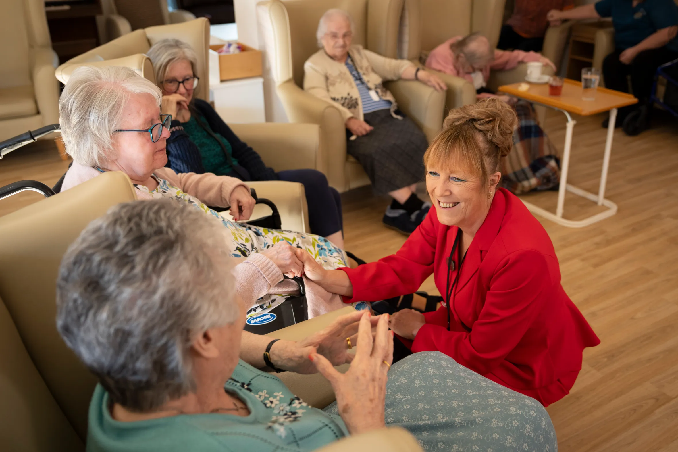 Kim Northwood smiling as she holds hands with an elderly resident at The Gables care home.