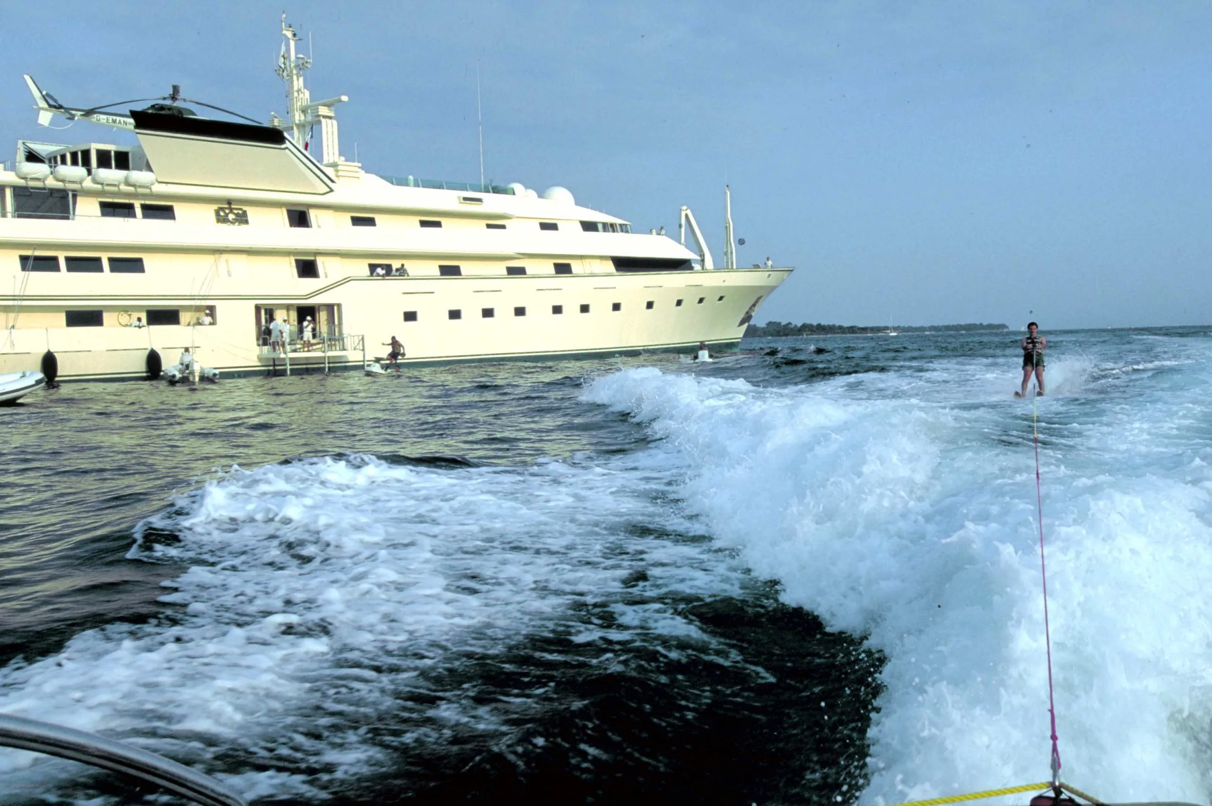 Prince Alwaleed water skiing behind a boat, with his yacht, the Kingdom 5-KR, visible in the background.