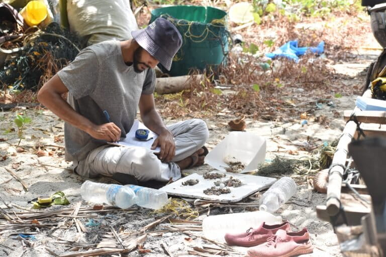 Researcher Mayur Fulmali sorts and measures hermit crab shells found inside plastic debris at Vikas Nagar beach on Kamorta Island. Plastic containers of various shapes and sizes can act as traps for hermit crab. Image by Vishnu T.
