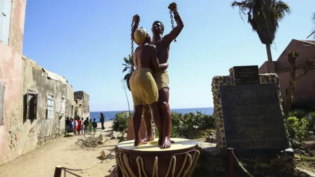 A statue of a man and a woman in chains at Goree Island for Senegal. Di place dey known as 'Island of Shame' due to di fact say e bin be a major outpost of di transatlantic slave trade between di 15th and 19th centuries.