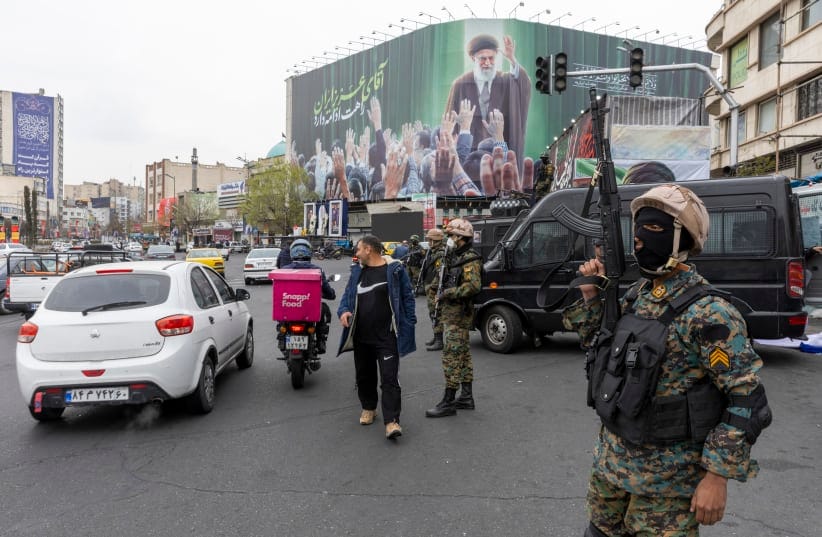 A police officer stands guard beneath a poster of Iran's former leader, Ayatollah Ali Khamenei on March 10, 2026 in Tehran, Iran.