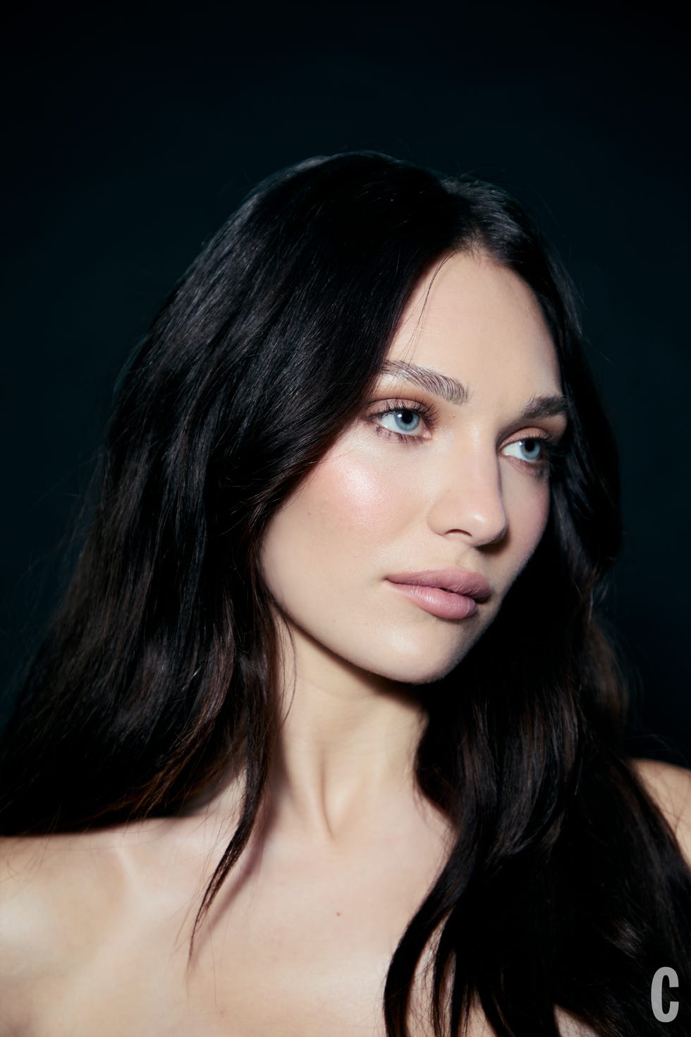 Portrait of a person with a blurred facial area against a dark background.