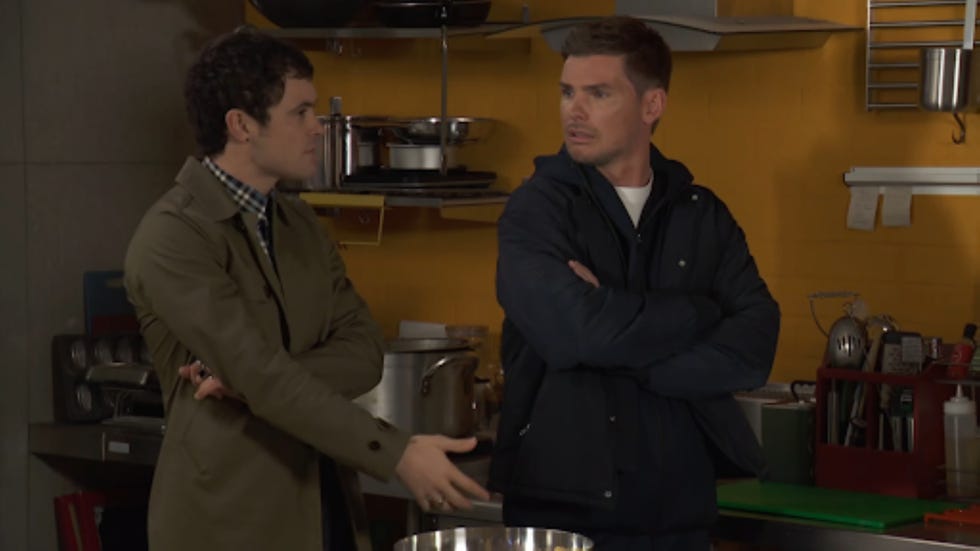 two individuals engaged in conversation in a kitchen setting