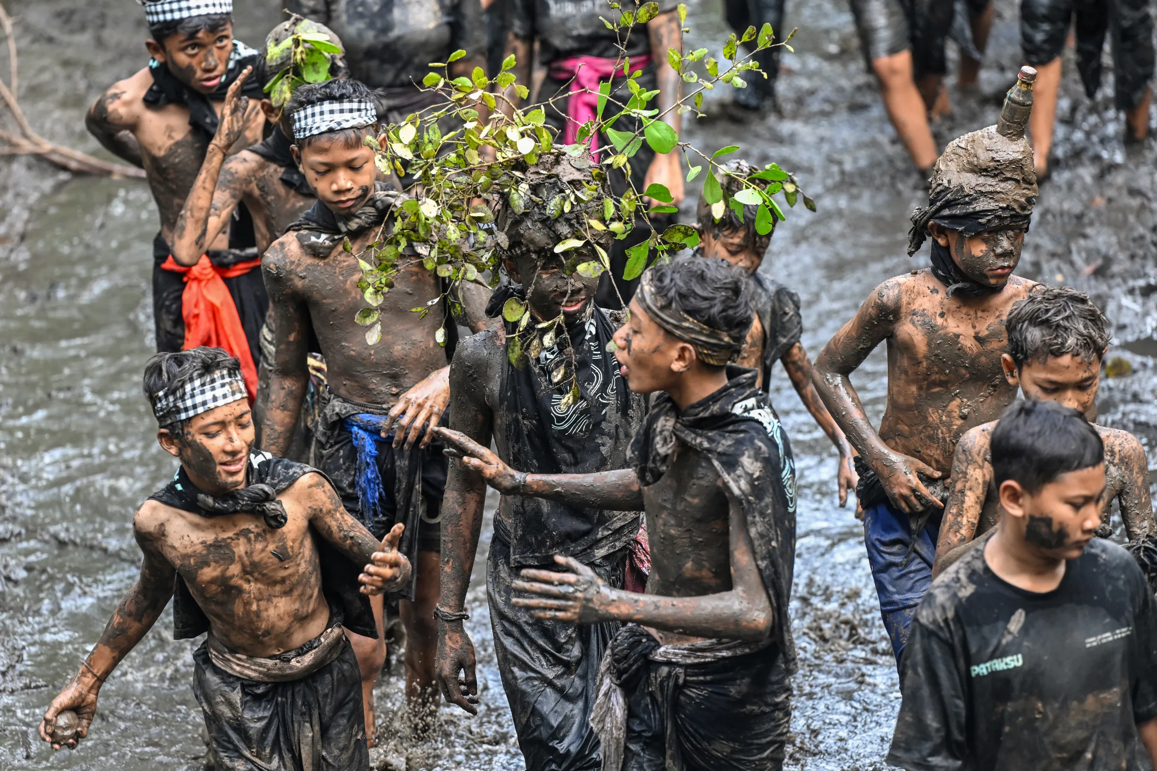 People covered in mud during the Mebuug-buugan purification ritual in Kedonganan village, Bali.
